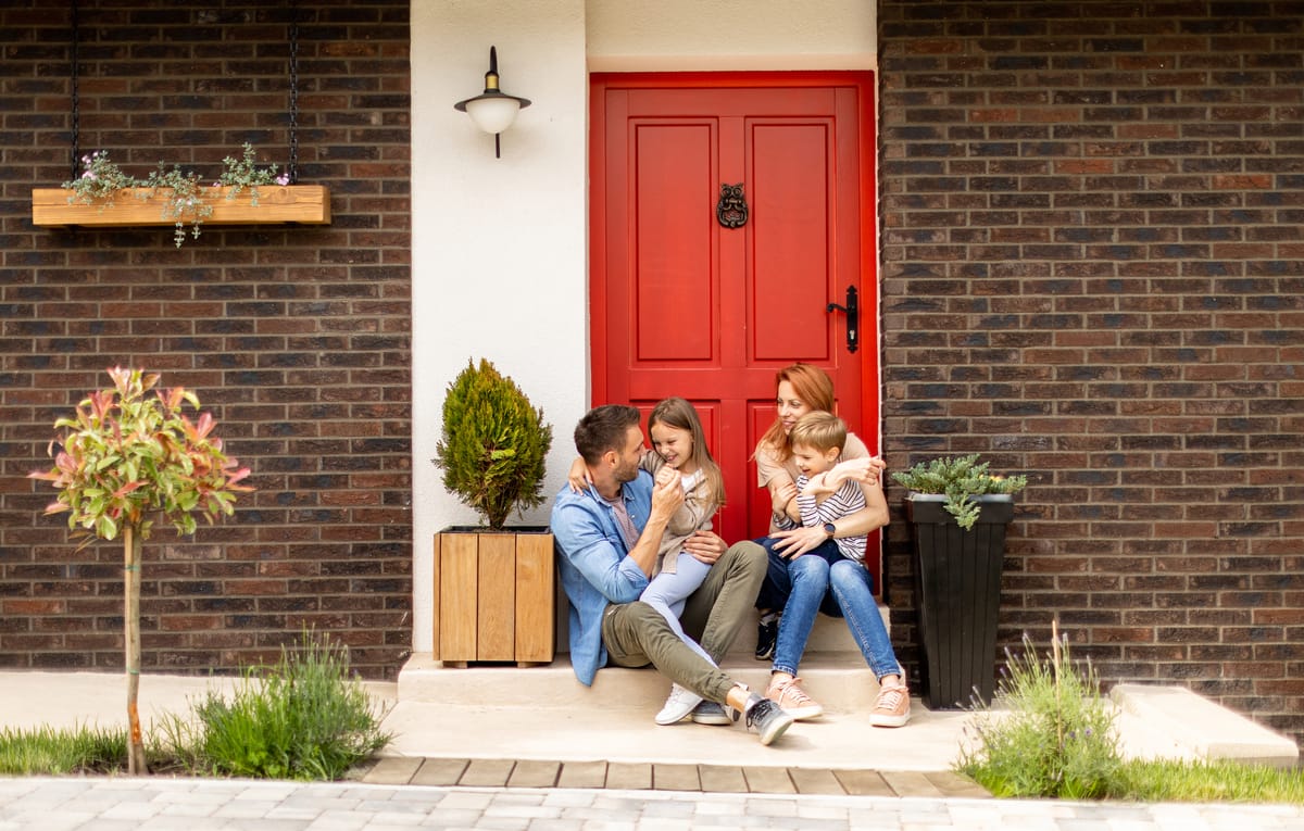 A family sitting together on the front step of a brick house